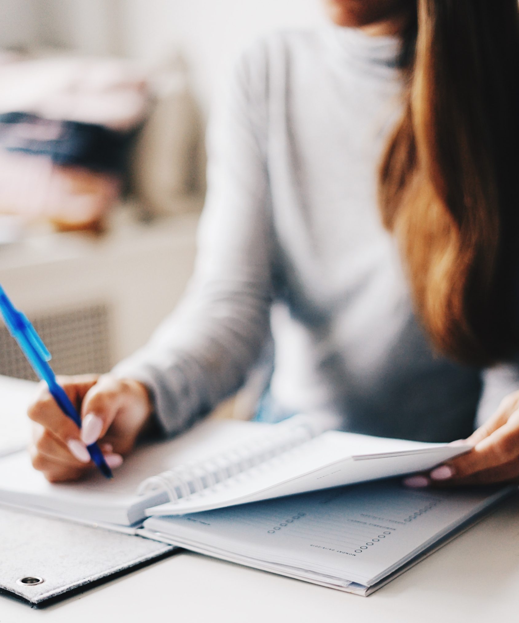 picture of girl sitting at desk writing on notepad